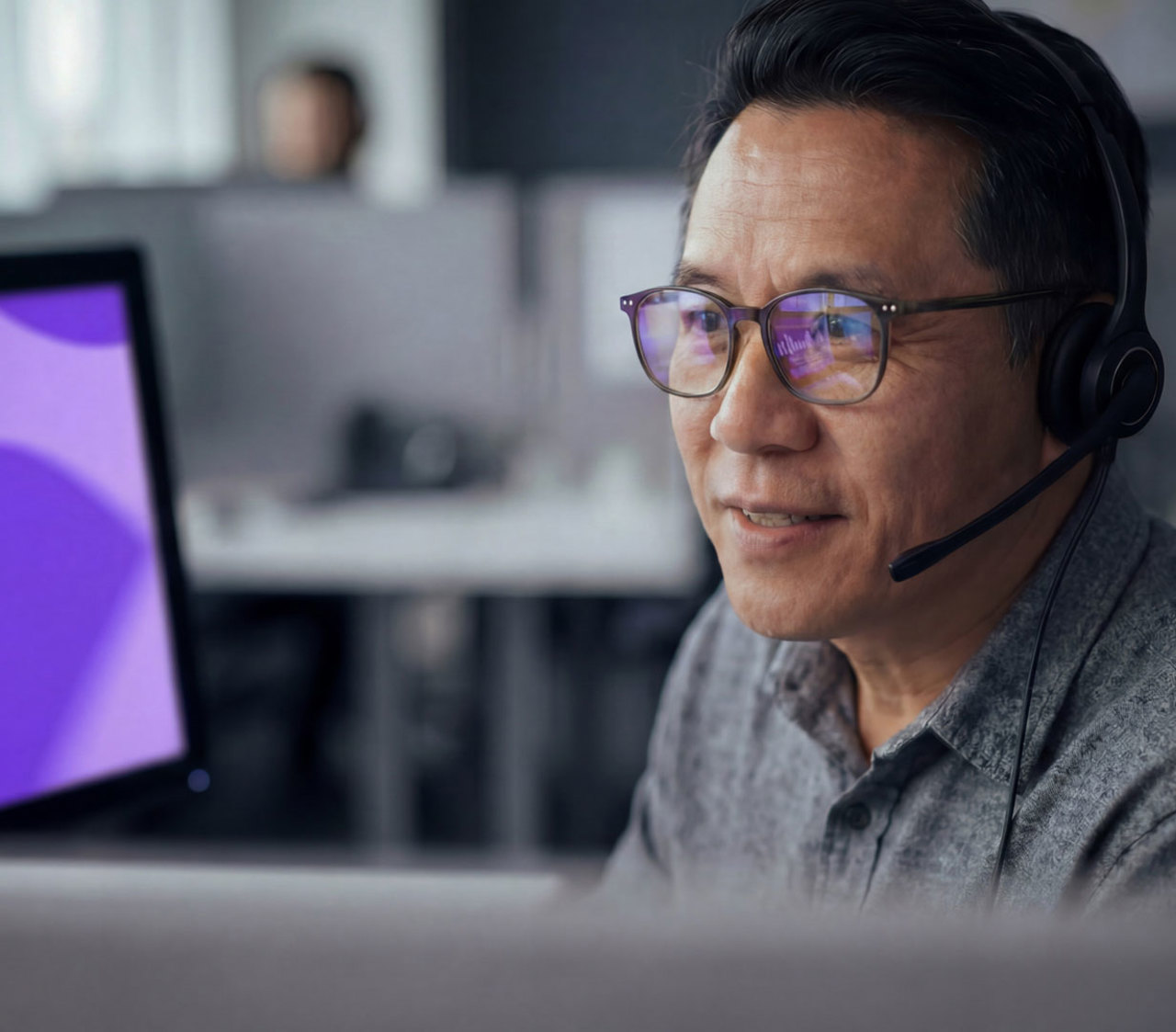 Call Center Mitarbeiter von Intrum mit Headset, vor einem Bildschirm